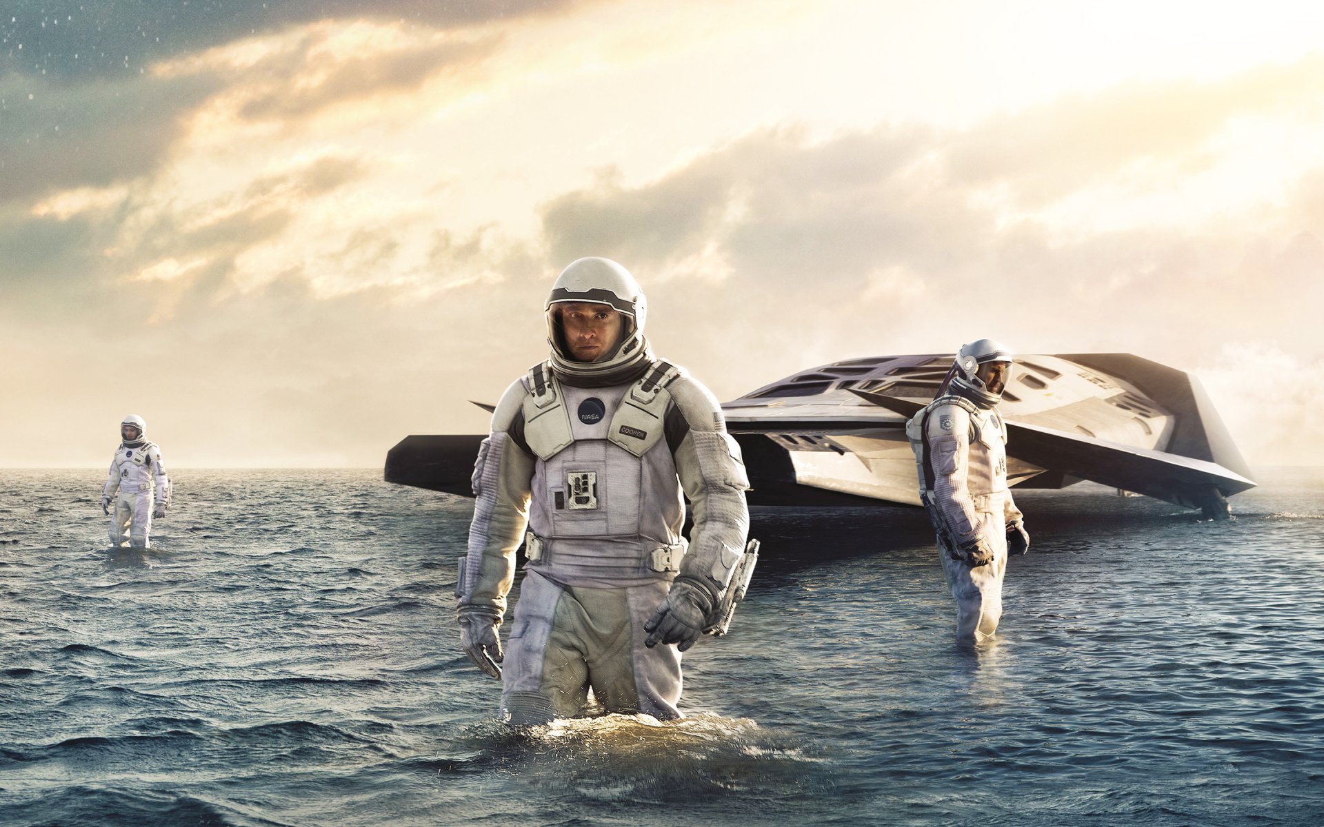 A striking HD desktop wallpaper featuring astronauts standing in shallow water beside a futuristic spaceship, inspired by the sci-fi movie Interstellar, under a dramatic sky.