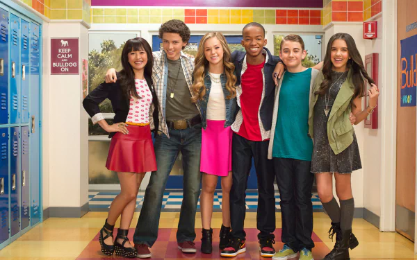 HD PC desktop wallpaper of the Bella and the Bulldogs TV show cast posing and smiling together in a bright, colorful school hallway background.