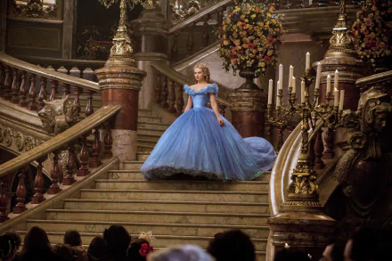 Lily James as Cinderella descends a grand staircase in a beautiful blue gown from the 2015 movie Cinderella, surrounded by elegant decor and warm candlelight.