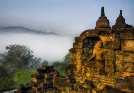 HD desktop wallpaper featuring a serene Buddhist statue in an ancient stone temple, with misty mountains and lush greenery in the background, symbolizing peace and spirituality.