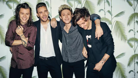 HD desktop wallpaper featuring One Direction members smiling and standing together against a leafy background.
