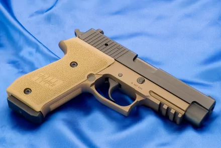 A high-definition desktop wallpaper featuring a Sig Sauer pistol against a smooth blue background, showcasing the firearm's detailed design and craftsmanship.