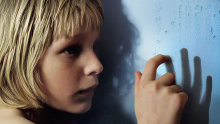 HD PC desktop wallpaper: close-up of a pale blond child pressing a hand to a fogged window, shadow cast on blue glass — moody scene from the movie Let the Right One In.
