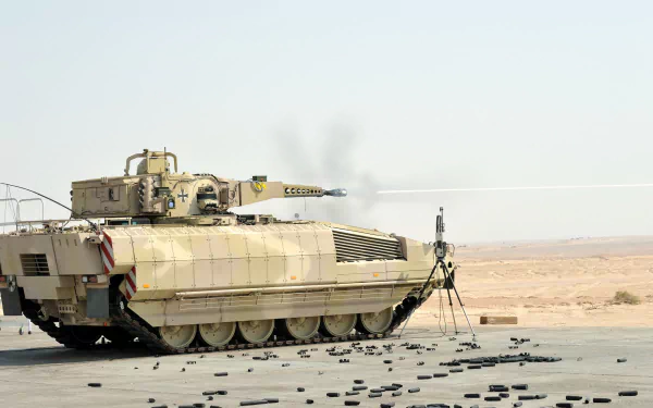 HD PC desktop wallpaper: military tan Puma IFV (infantry fighting vehicle) parked on desert asphalt, spent shell casings scattered under a clear sky.