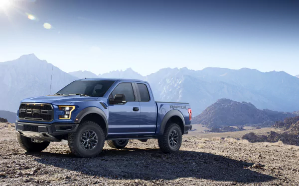 4K Ultra HD desktop wallpaper featuring a blue Ford Raptor truck parked on rocky terrain with mountains and a clear sky in the background.