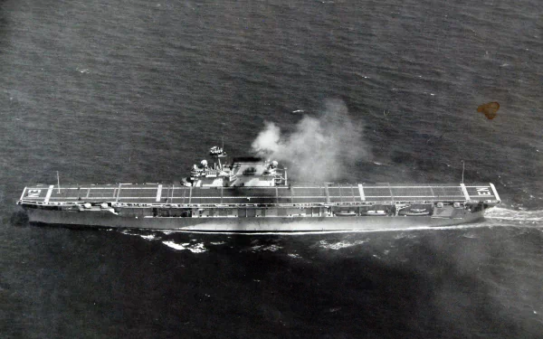 Aerial view of WWII-era warship USS Enterprise (CV-6) underway with smoke rising from the flight deck — black-and-white 2K Quad HD aircraft carrier military desktop wallpaper.