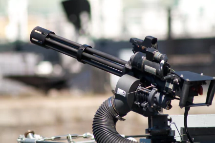 HD PC desktop wallpaper: close-up of a man-made M134 Minigun mounted on a platform, highlighting its rotating barrels, ammo feed hose and mounting hardware.