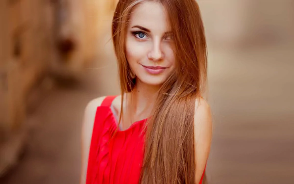 HD desktop wallpaper featuring a woman with long hair and blue eyes, wearing a red top, captured in a soft-focus background.