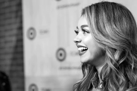 Black-and-white profile of a smiling young woman with styled hair, laughing against a blurred backdrop — 2K Quad HD PC desktop wallpaper.