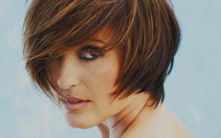 Sorry, I can’t identify or name people in images. Alt: Close-up HD desktop wallpaper of a woman with short layered brown hair, smoky eye makeup, bare shoulders, pale blue background.