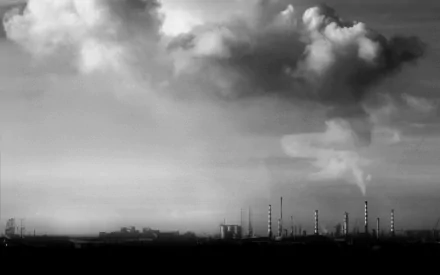 An atmospheric black-and-white image of a factory skyline, featuring smokestacks and dramatic clouds, serves as an engaging HD desktop wallpaper and background.