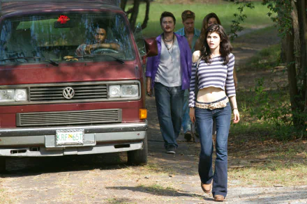 An HD desktop wallpaper featuring a scene from Texas Chainsaw 3D, showcasing Alexandra Daddario walking confidently with a group of friends by a vintage van.