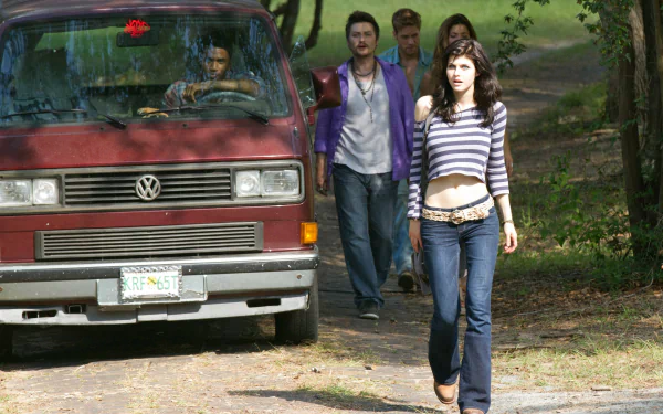 An HD desktop wallpaper featuring a scene from Texas Chainsaw 3D, showcasing Alexandra Daddario walking confidently with a group of friends by a vintage van.