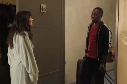 HD desktop wallpaper: a scene from the sitcom New Girl — a woman in a light coat smiles as a man with luggage stands in a doorway.