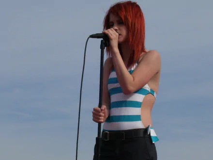 Hayley Williams performing on stage, wearing a striped outfit. This high-definition image serves as a vibrant desktop wallpaper, celebrating her music and energy.