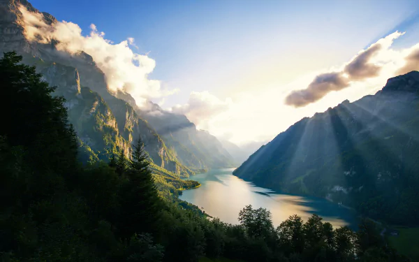 A stunning valley landscape with a river winding through lush greenery, framed by majestic mountains and a sky filled with dramatic clouds, captured in 4K Ultra HD quality.