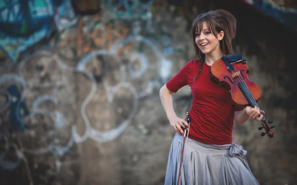 HD PC desktop wallpaper featuring musician Lindsey Stirling holding a violin and smiling against an artistic, graffiti-covered background.