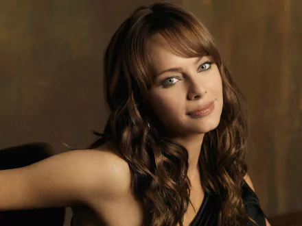 HD PC desktop wallpaper featuring a close-up portrait of celebrity Melinda Clarke against a warm brown background.