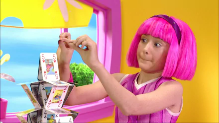 HD PC desktop wallpaper from the TV show LazyTown featuring a young girl with bright pink hair building a house of cards inside a colorful room.