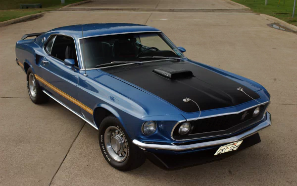 Blue Ford Mustang Mach 1 fastback muscle car with black hood scoop, parked on pavement — 2K Quad HD PC desktop wallpaper/background.