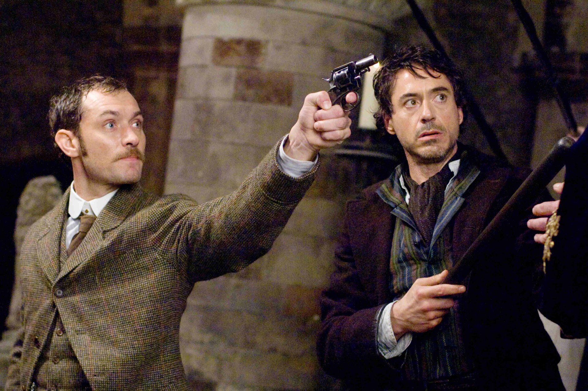Cinematic Sherlock Holmes movie scene: two men in Victorian attire in a tense standoff — one aiming a pistol — 2K Quad HD PC desktop wallpaper.