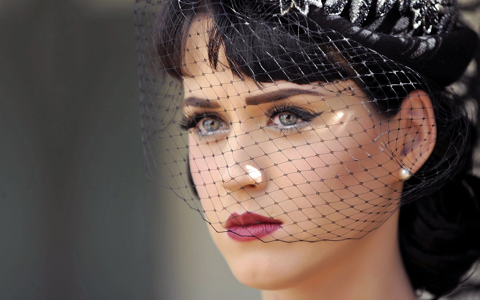 HD desktop wallpaper featuring a close-up of Katy Perry with bold makeup and a black netted veil, highlighting her striking eyes and elegant style in a music-themed image.