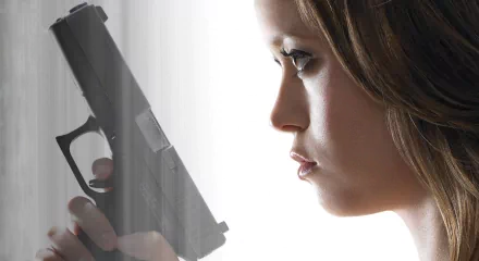 A striking HD desktop wallpaper from Terminator: The Sarah Connor Chronicles, featuring a close-up of a determined woman holding a handgun, embodying tension and resilience.