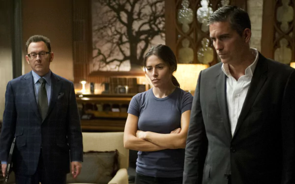 HD desktop wallpaper featuring Sarah Shahi, Jim Caviezel, and Michael Emerson from the TV show Person of Interest in a serious indoor scene.