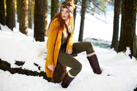 Woman in a mustard coat and headband seated on a snow-covered log in a sunlit pine forest — 5K Ultra HD PC desktop wallpaper background