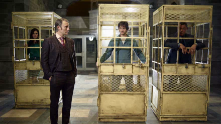 HD PC desktop wallpaper from the TV show Hannibal: a tense holding room with three people in metal cages and a man standing outside, dim, moody lighting.