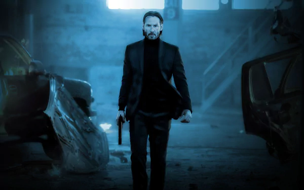 A striking HD wallpaper featuring Keanu Reeves as John Wick, confidently walking through a dimly lit, abandoned space with a gun in hand.
