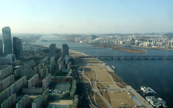Aerial view of Seoul showcasing a blend of urban buildings, a river, and a bridge under a clear sky. HD desktop wallpaper and background.