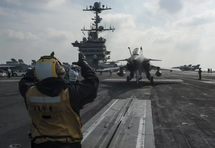 USS Harry S. Truman aircraft carrier with a Dassault Rafale jet preparing for takeoff on deck under a cloudy sky in this HD military wallpaper.