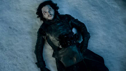 Jon Snow, portrayed by Kit Harington, lies on the snow in this captivating HD wallpaper from the TV show Game of Thrones, capturing a dramatic moment from the series.