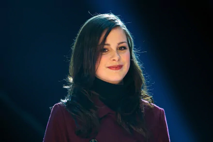 Lena Meyer-Landrut smiles confidently in a spotlight, showcasing her vibrant presence in this HD desktop wallpaper. A striking background that captures the essence of music.