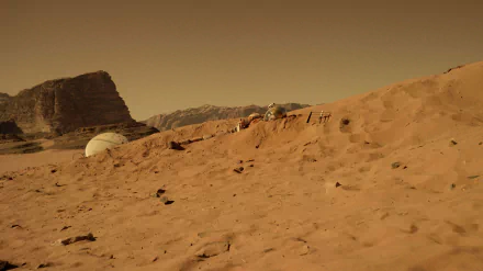 HD desktop wallpaper from the movie The Martian, depicting a barren, reddish Martian landscape with a habitat dome and rocky hills under a hazy sky.