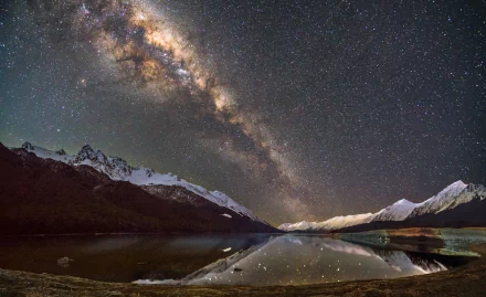 A stunning HD wallpaper capturing the Milky Way over snow-capped mountains, reflecting on a serene lake, creating a breathtaking sci-fi nightscape filled with stars.