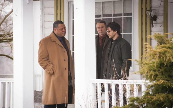 Three male cast members from the TV show Hannibal stand on a snowy porch in overcoats; cinematic 2K Quad HD PC desktop wallpaper.