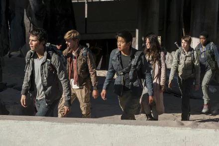 A group of characters from Maze Runner: The Scorch Trials, featuring Dylan O'Brien, Ki Hong Lee, Kaya Scodelario, and Thomas Brodie-Sangster, walking through a desolate landscape.