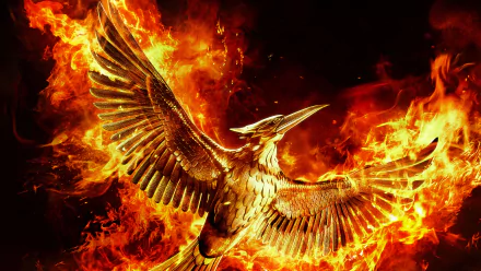8K Ultra HD PC desktop wallpaper: flaming gold Mockingjay emblem from The Hunger Games: Mockingjay – Part 2, wings spread amid a roaring orange-red inferno.