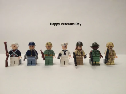 HD PC desktop wallpaper featuring seven LEGO figures dressed in various military uniforms with the text Happy Veterans Day above, commemorating the holiday.