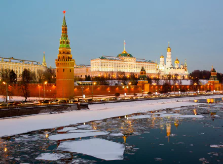 A serene winter scene featuring the Moscow Kremlin alongside a frozen river, illuminated by twilight, capturing the beauty of ice and architecture in Russia's capital.