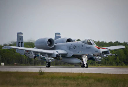 HD desktop wallpaper featuring a Fairchild Republic A-10 Thunderbolt II military aircraft on a runway with a forested background.