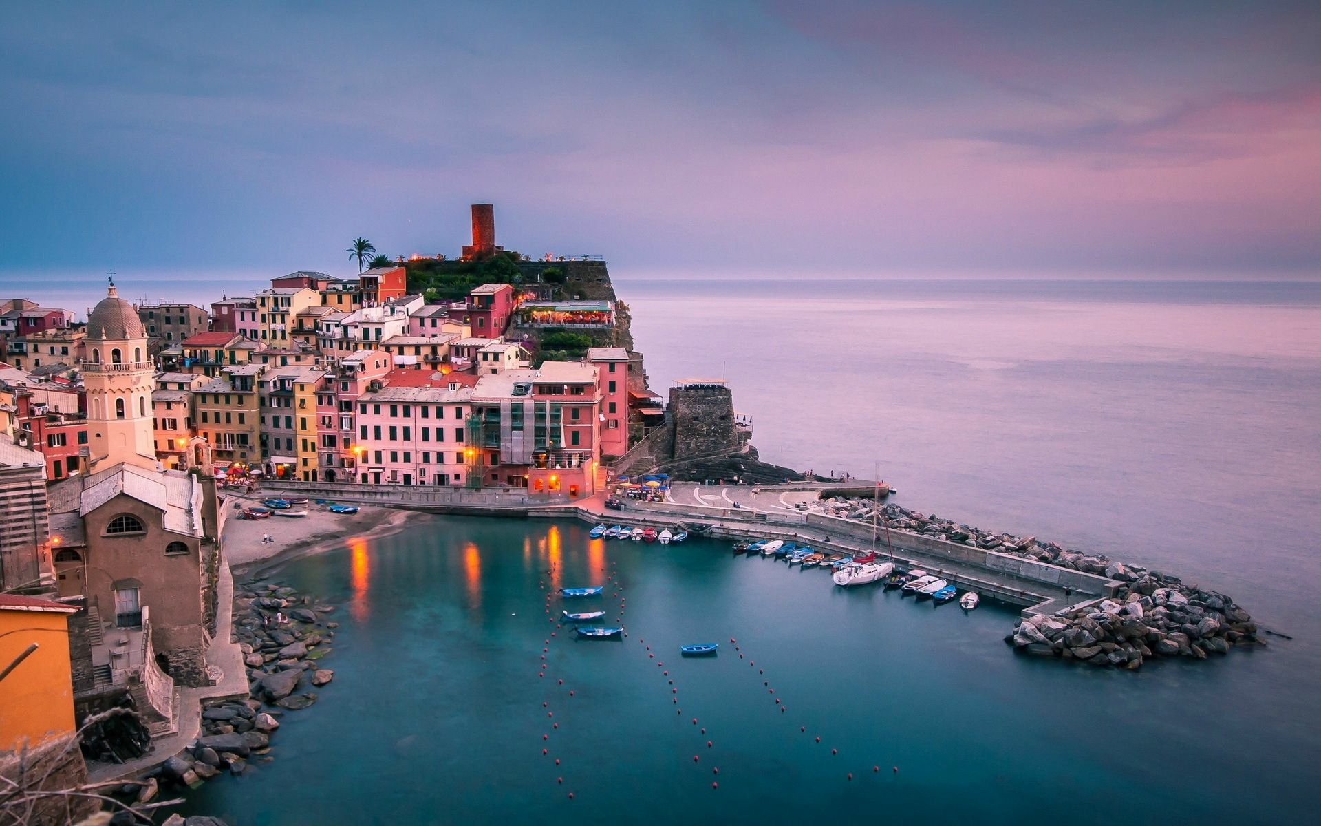 Colorful buildings and boats line the tranquil harbor of Vernazza by the ocean, captured in a vibrant HD desktop wallpaper background.