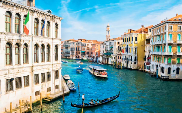 4K Ultra HD view of Venice's iconic canal with gondolas and colorful historic buildings under a bright blue sky, showcasing the charm of this man-made Italian cityscape.
