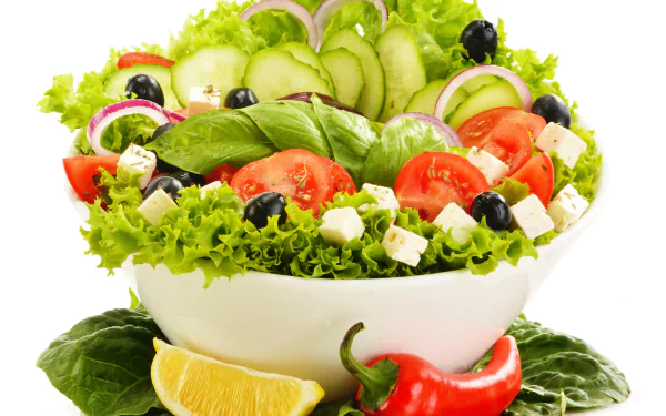 Colorful salad food: cucumber, tomato, olives, feta, lemon wedge and red pepper in a white bowl, fresh greens on a 4K Ultra HD PC desktop wallpaper/background.