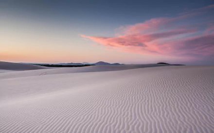 HD desktop wallpaper featuring a serene desert landscape with smooth sand dunes under a vibrant sky dotted with clouds at sunset.