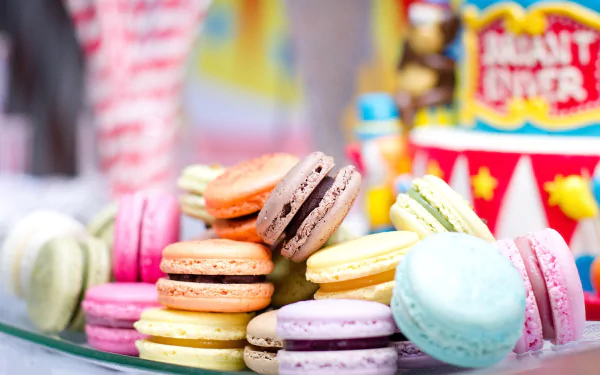 A colorful arrangement of macarons in various shades on a glass plate, set against a vibrant background, showcasing a delightful dessert experience. Perfect for a food-themed desktop wallpaper.
