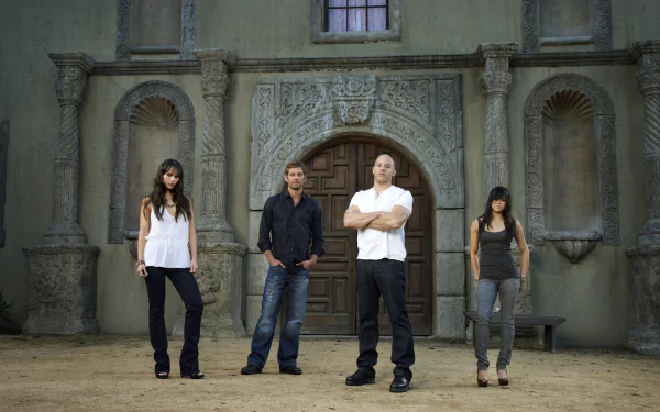 HD desktop wallpaper featuring Letty Ortiz, Mia Toretto, Brian O'Conner, and Dominic Toretto from the Fast & Furious movie series, standing in front of an ornate building.