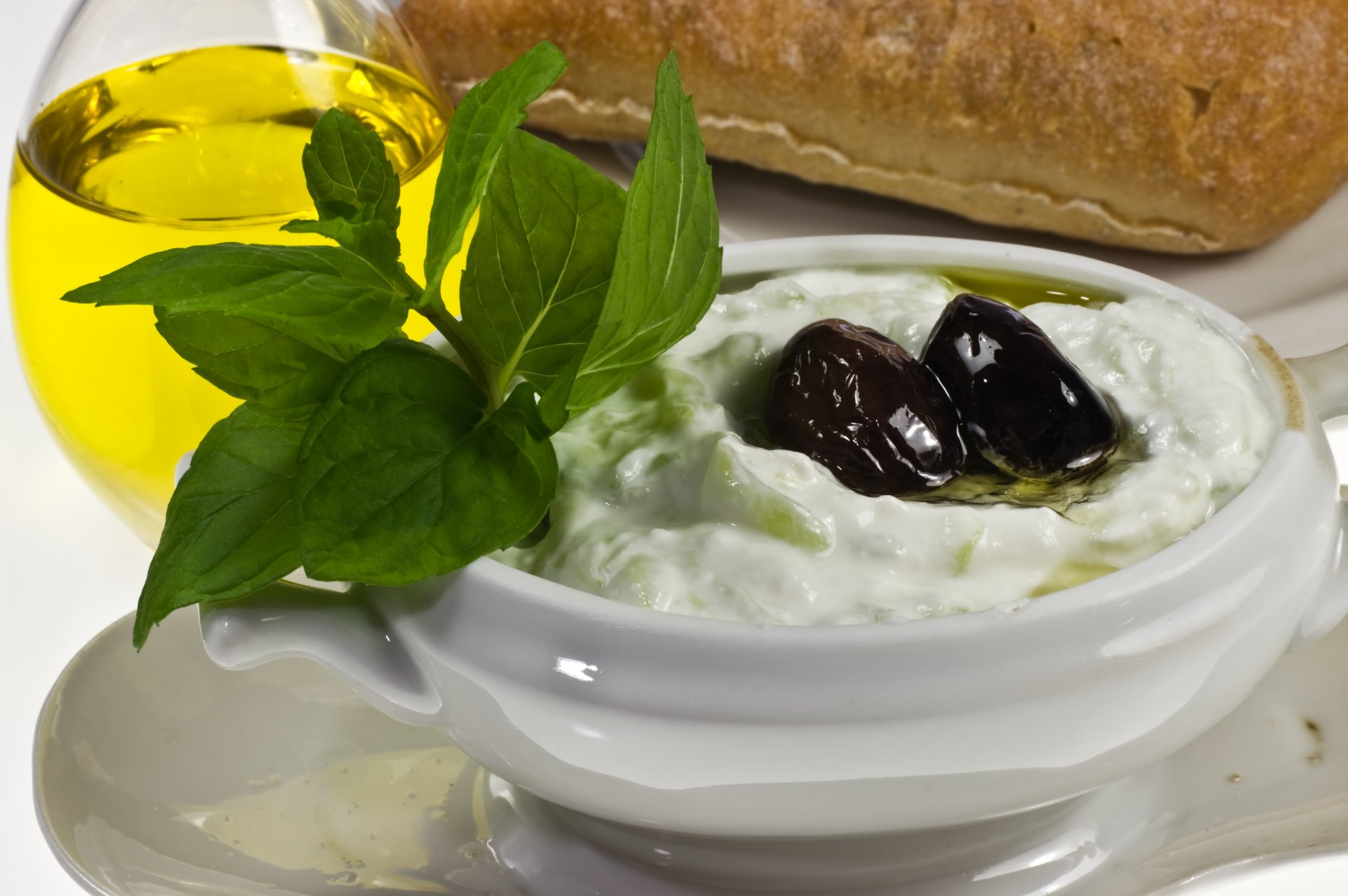 4K Ultra HD PC desktop wallpaper: close-up of creamy tzatziki in a bowl topped with olives and olive oil, garnished with fresh mint, with bread in the background.